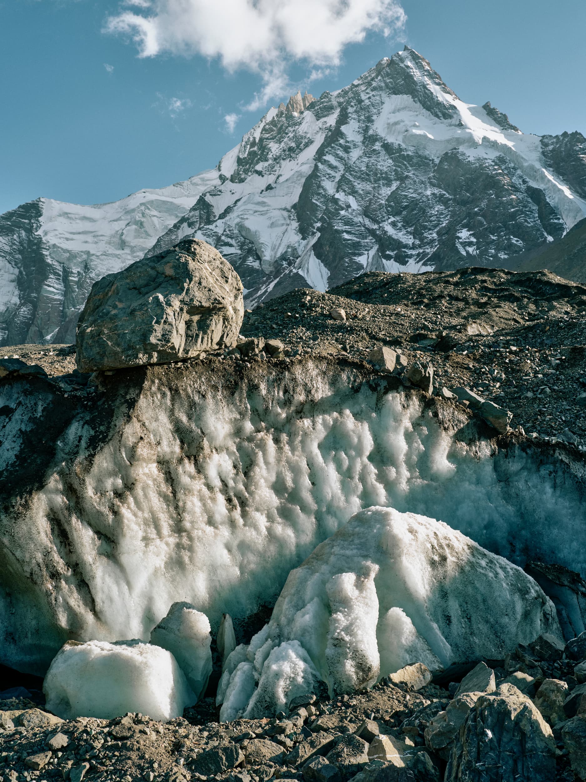 Schneebedeckter Berg mit Gletscher und Felsen im Vordergrund.