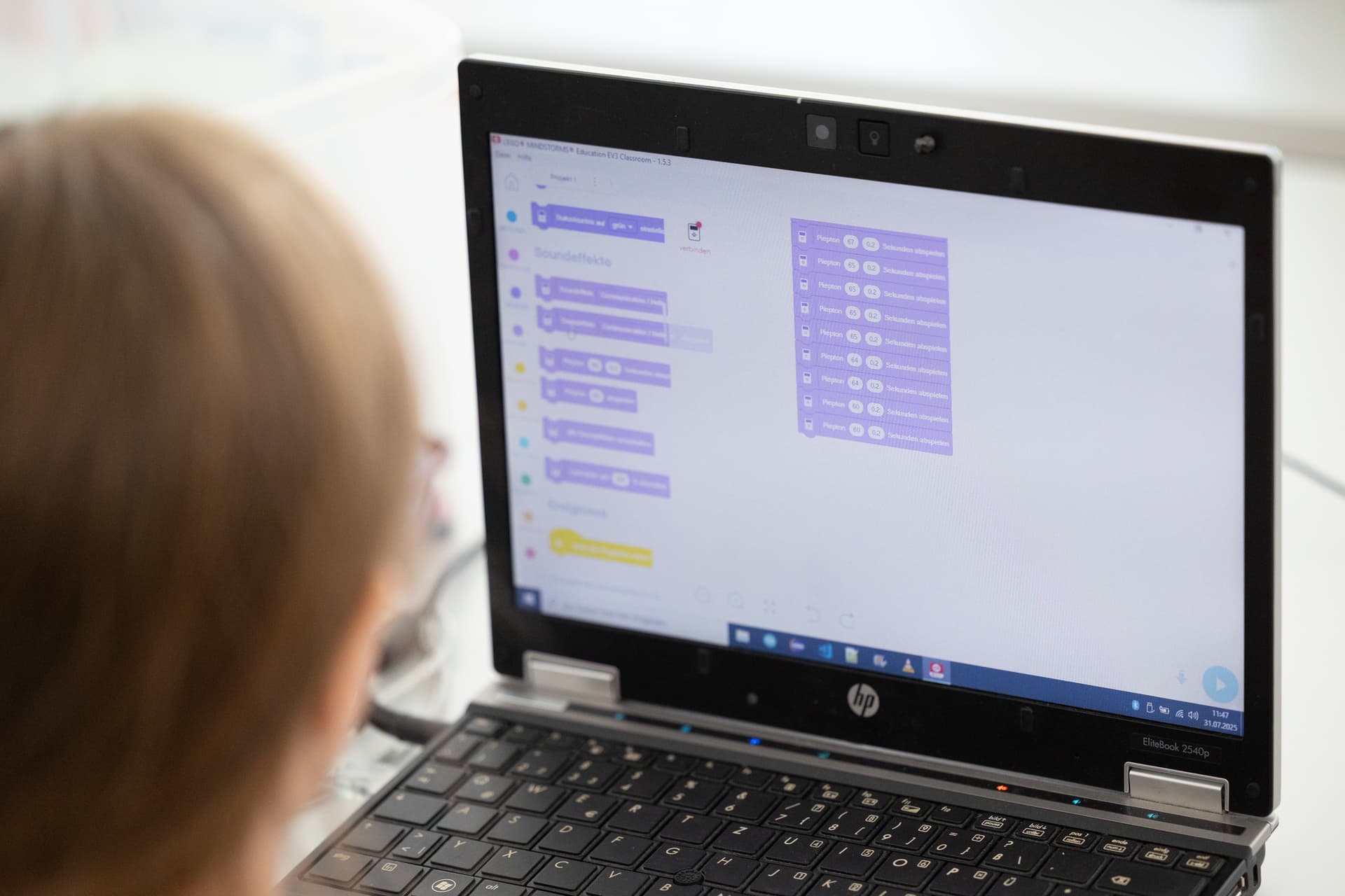 Eine Person, die auf einen Laptop-Bildschirm mit einer blockbasierten Programmiersoftware schaut und wahrscheinlich mit Programmier- oder Bildungsaktivitäten beschäftigt ist.